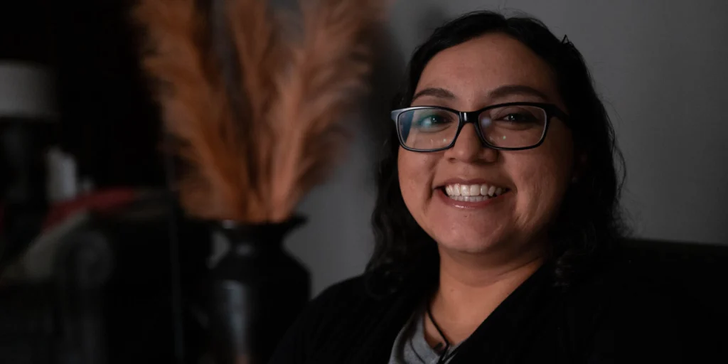 Smiling therapist in a cozy office setting with decorative pampas grass in the background
