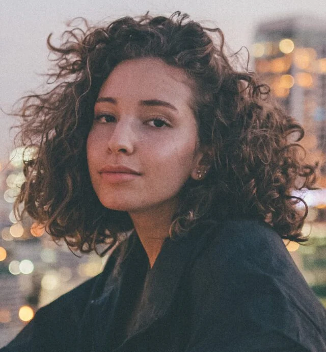 Portrait of teenage woman with city lights behind her