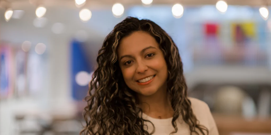 Smiling person in warmly lit office with string lights, embodying a welcoming and relaxed atmosphere at GearingUP Counseling